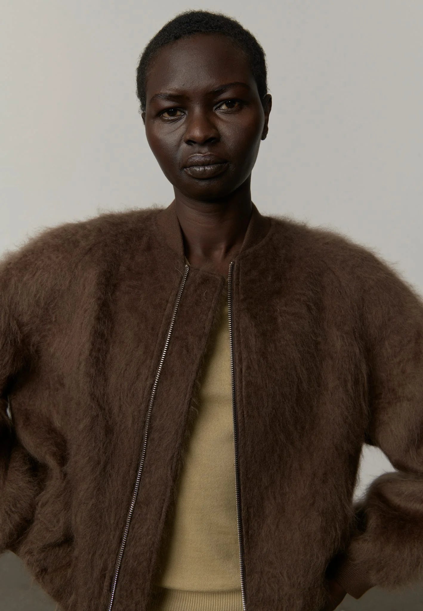 Person wearing a brown fur coat against a plain background