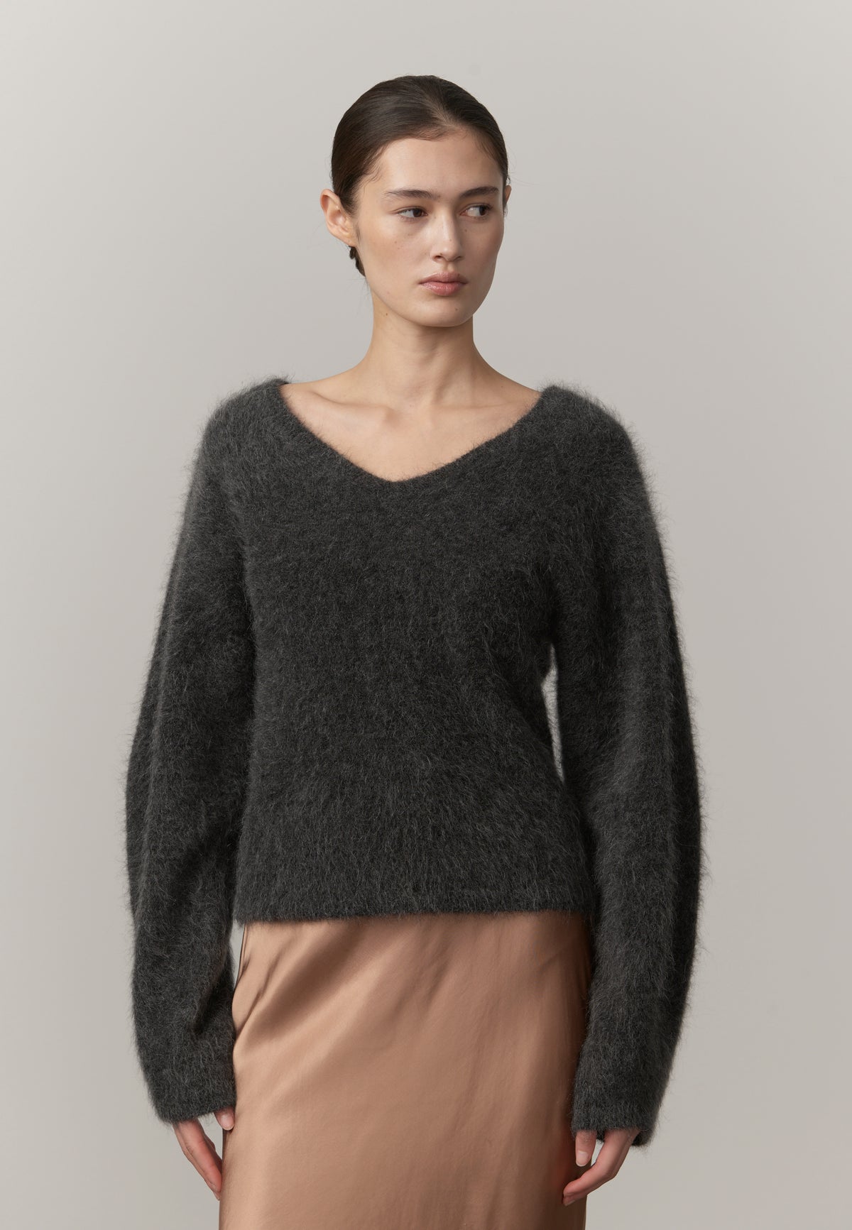 Woman wearing a dark gray sweater against a plain background