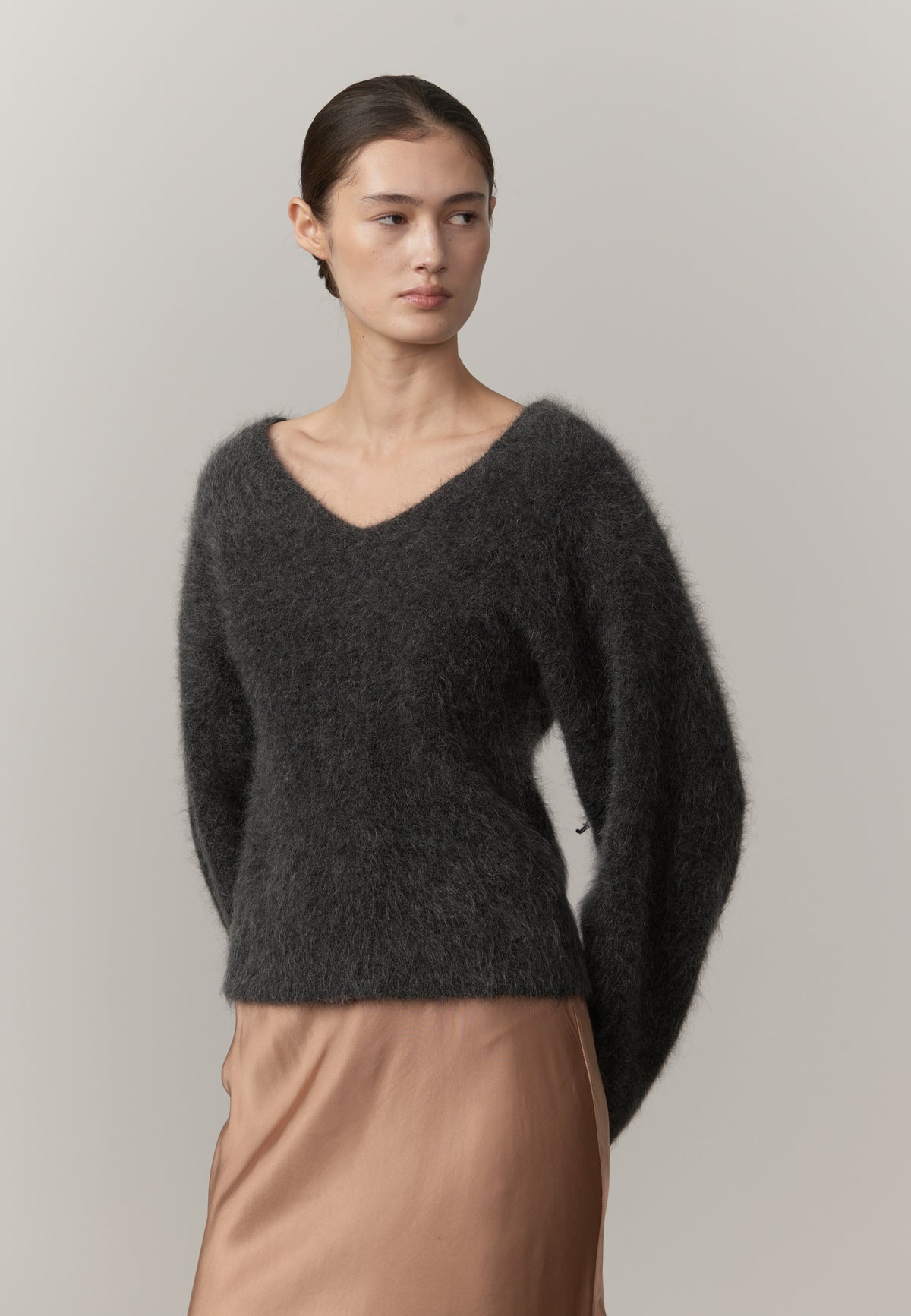 Woman wearing a dark gray sweater against a plain background