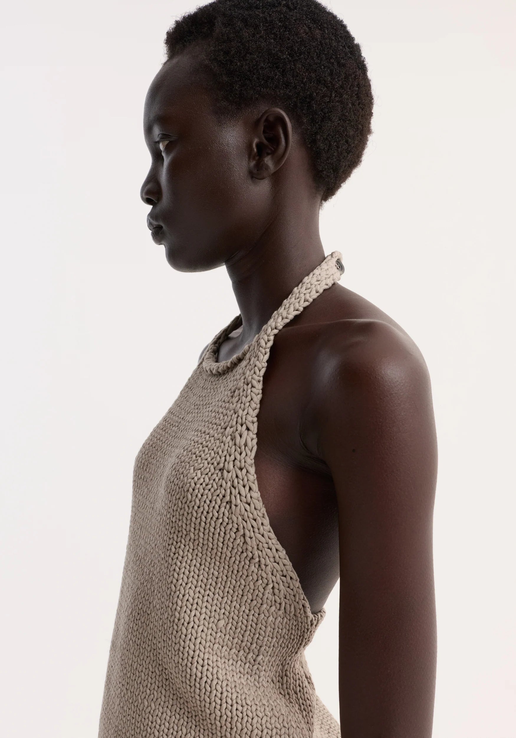 Woman wearing a beige knitted top against a white background