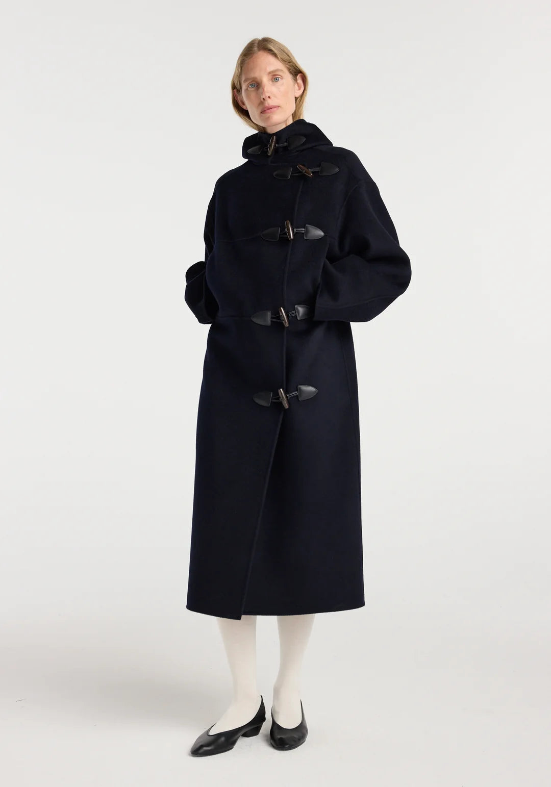 Woman wearing a long black coat on a white background