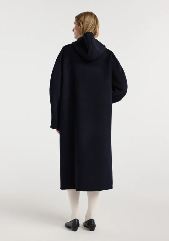 Person wearing a long black coat on a white background