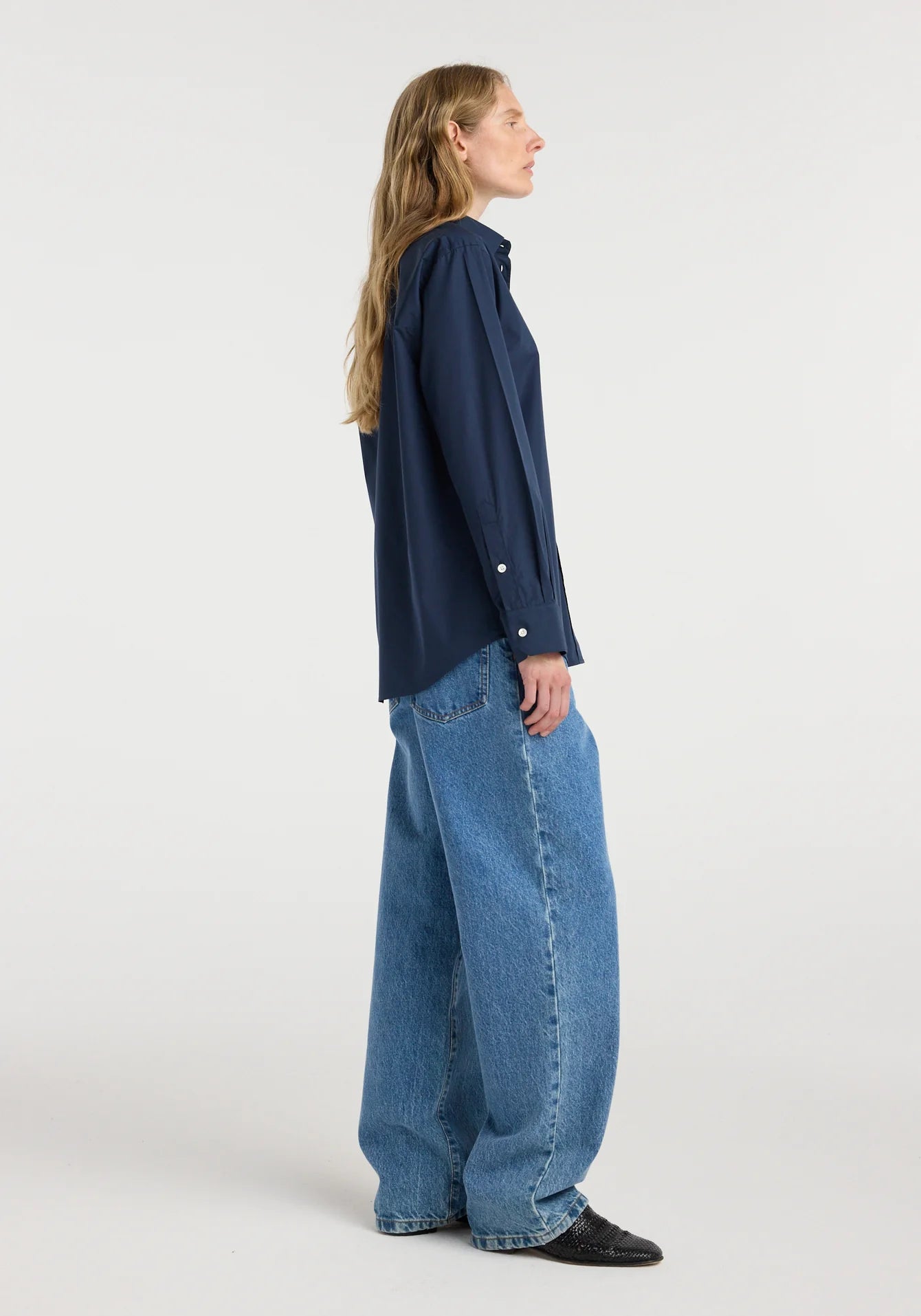 Person wearing a navy shirt and blue jeans on a white background
