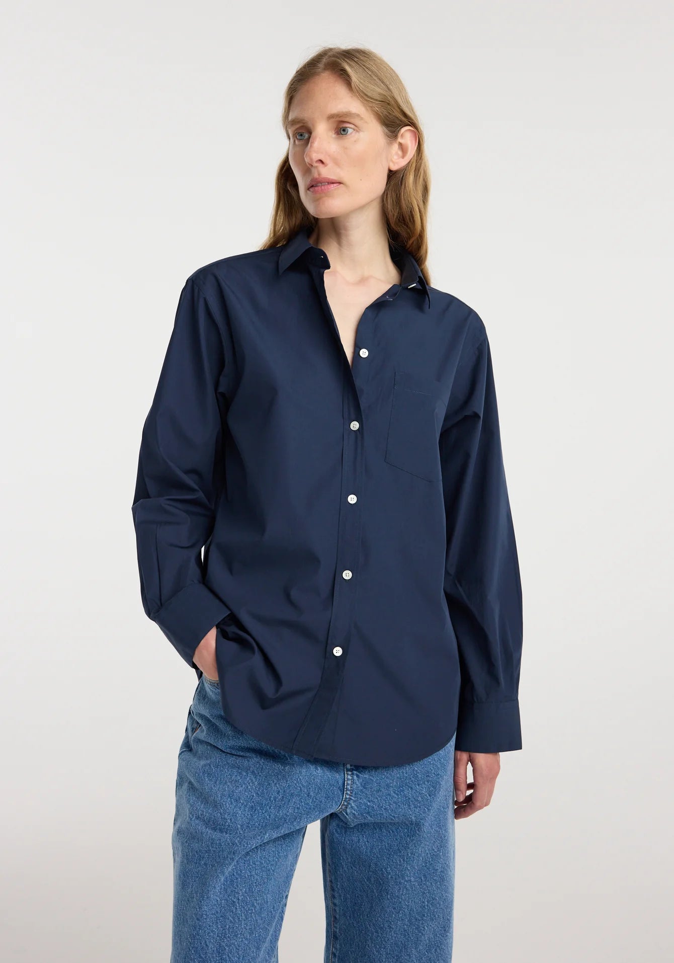 Woman wearing a navy blue shirt and blue jeans on a white background