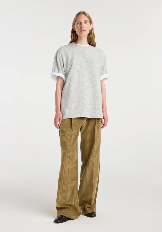 Person wearing a light gray t-shirt and beige pants on a white background