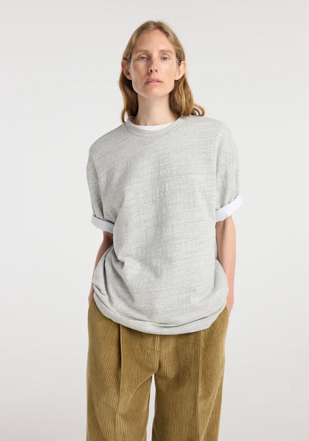 Person wearing a gray oversized t-shirt and brown pants on a white background