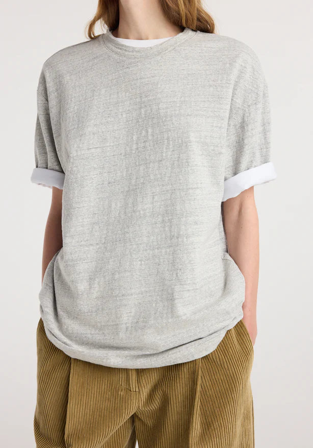Person wearing a gray t-shirt with white trim and brown pants on a white background