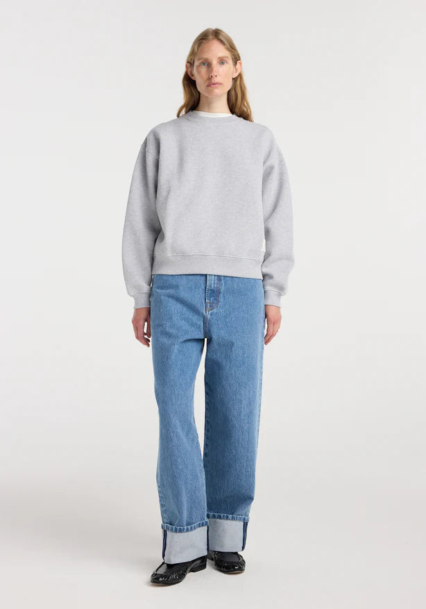 Person wearing a gray sweatshirt and blue jeans on a white background