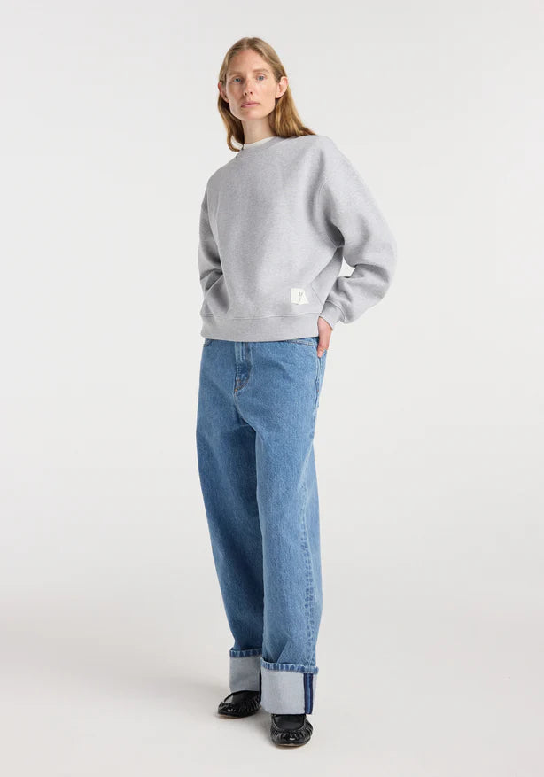 Person wearing a gray sweater and blue jeans on a white background