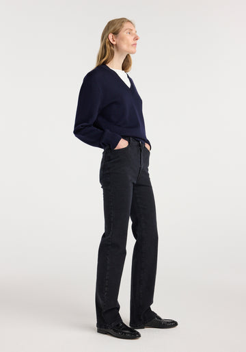 Person wearing a navy sweater and black pants on a white background