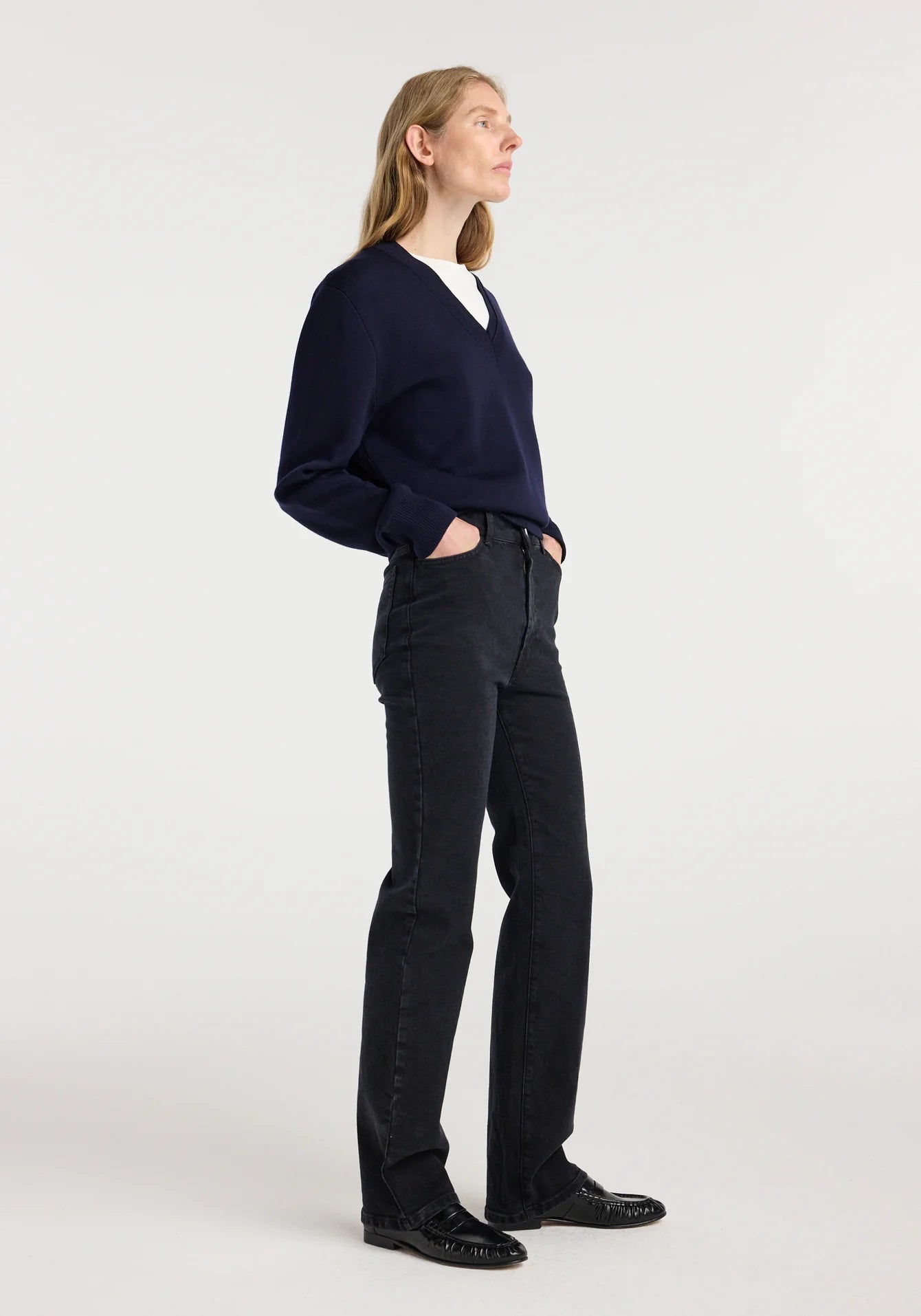 Person wearing a navy sweater and black pants on a white background