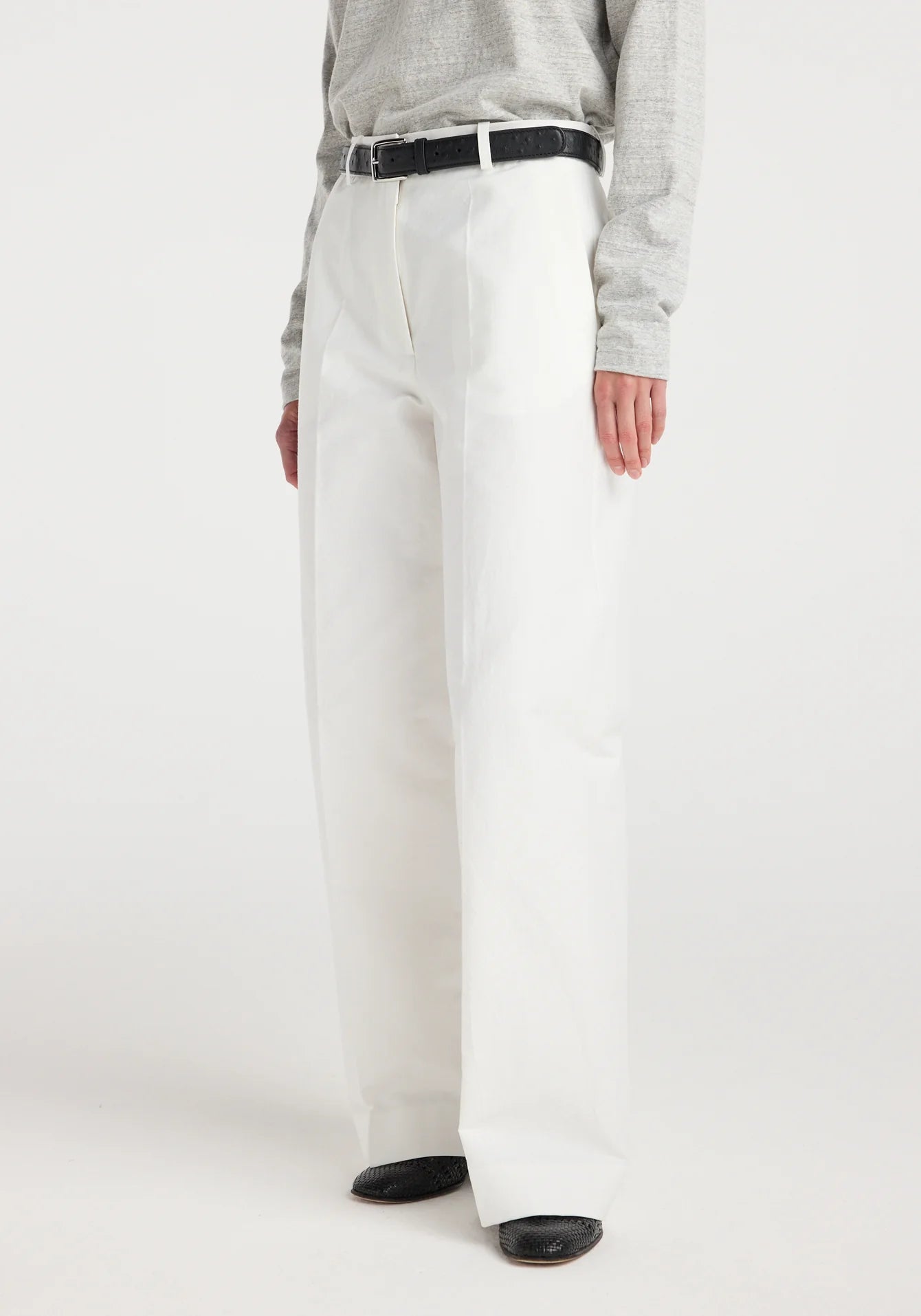 Person wearing white pants with a gray shirt on a white background