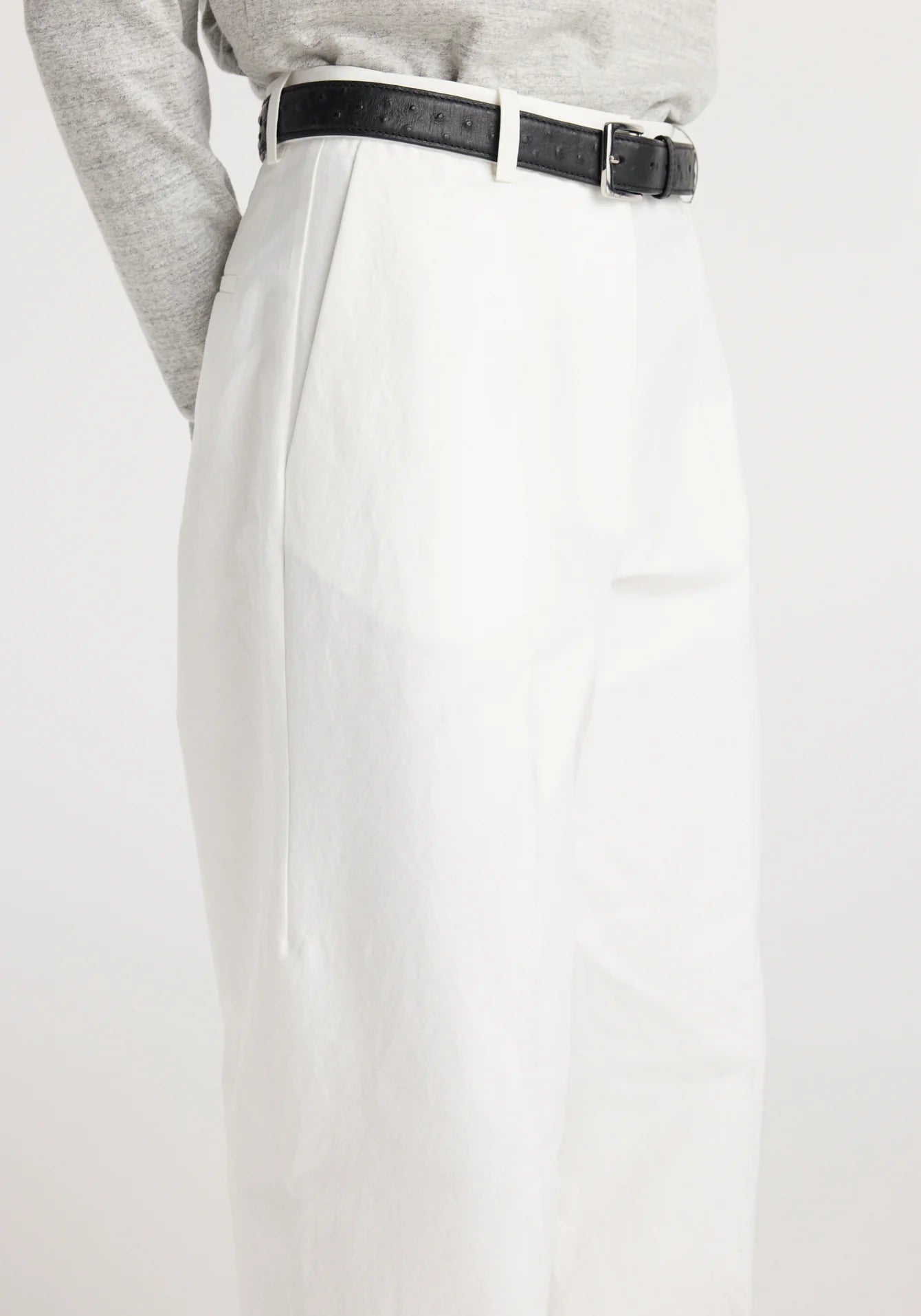White pants with a black belt worn by a person on a white background