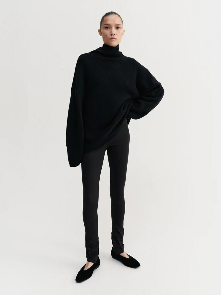 Person wearing a black turtleneck sweater and pants on a white background