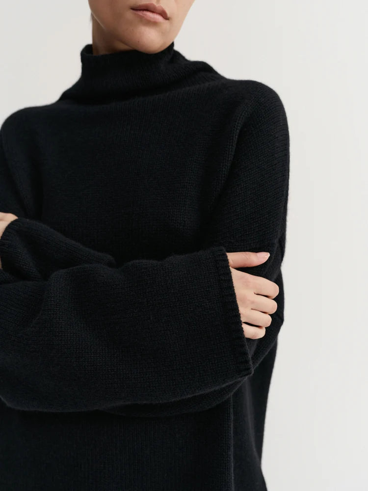 Person wearing a black turtleneck sweater on a light gray background