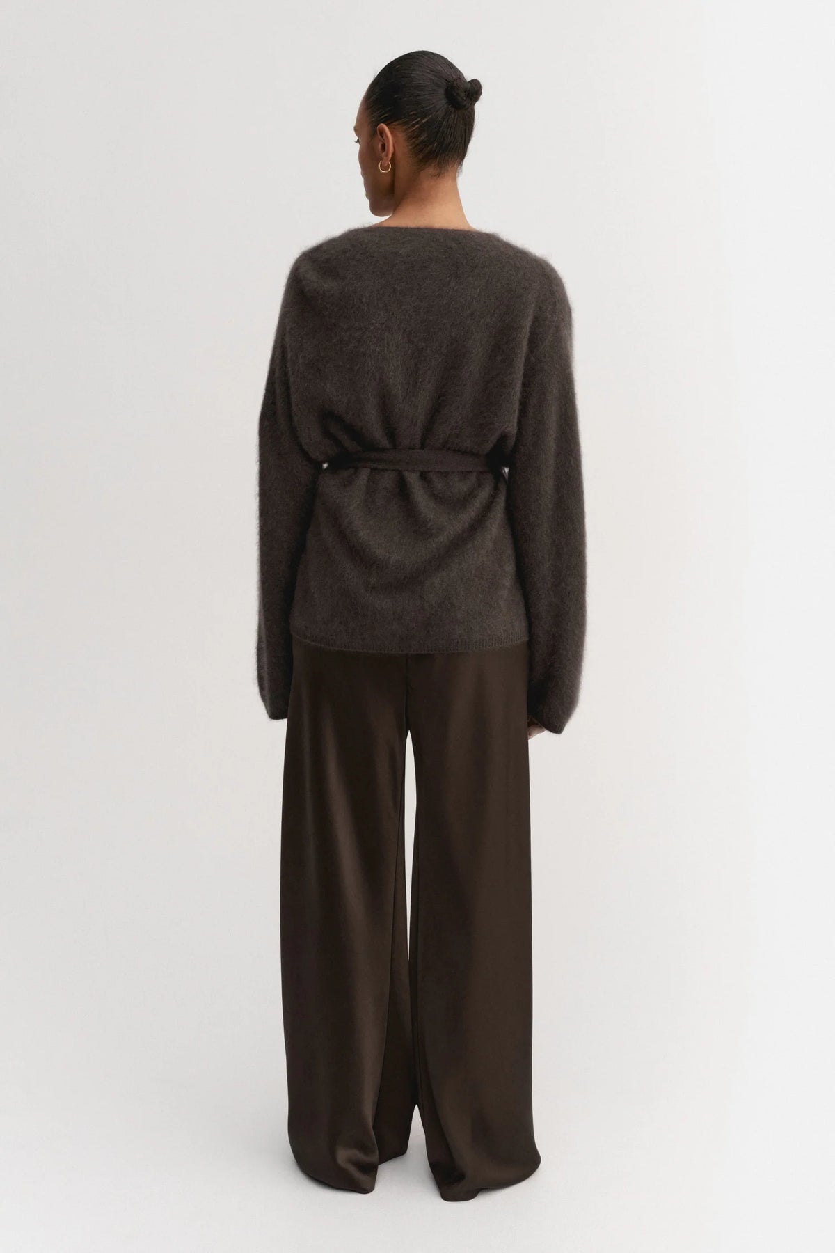 Person wearing a dark gray sweater and wide-leg pants on a white background