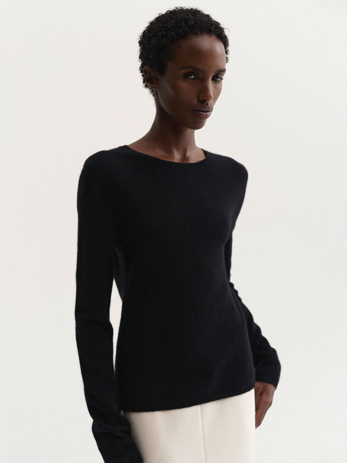 Woman wearing a black long-sleeve top against a white background