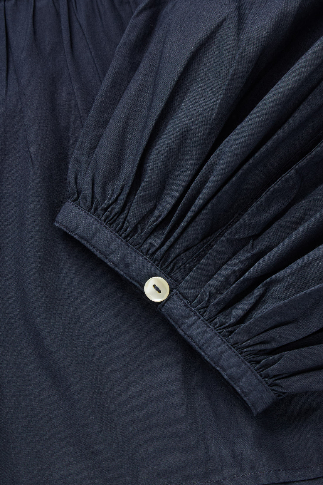 Close-up of a navy blue garment with a button detail