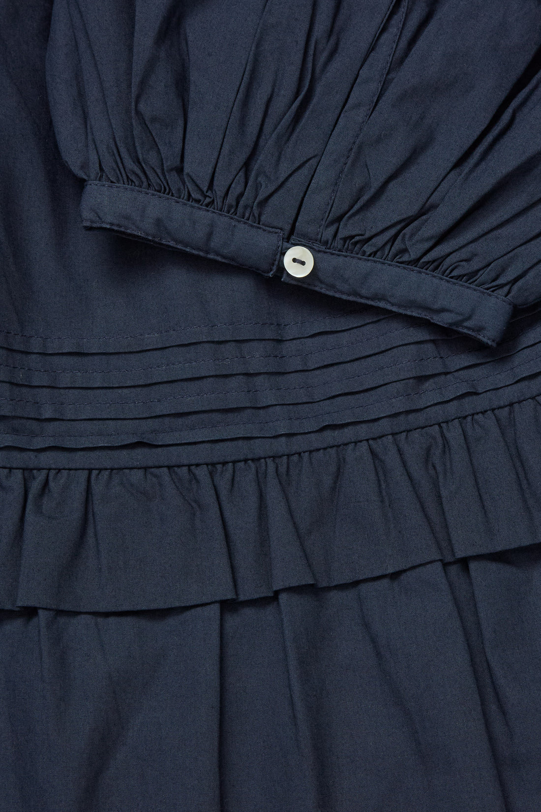 Navy blue dress with a button detail on a dark background