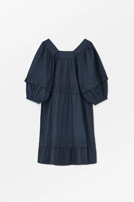 Navy blue dress with ruffled sleeves and bottom on a white background