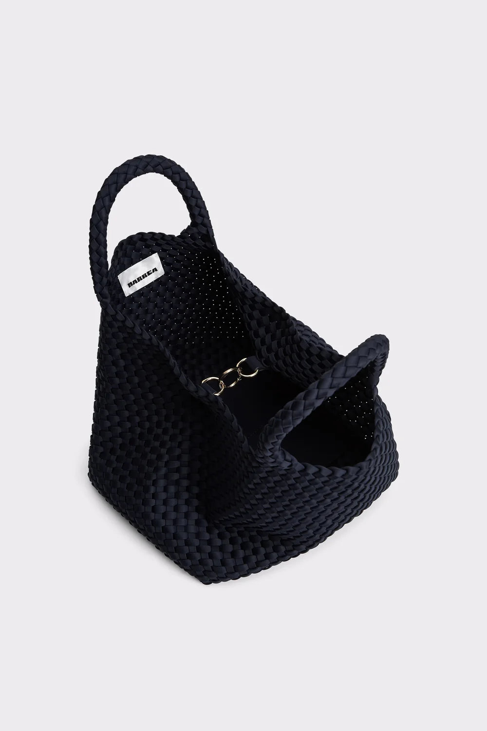 A black woven rope handbag with a single top handle and a small silver metal ring detail, shown on a light gray background.