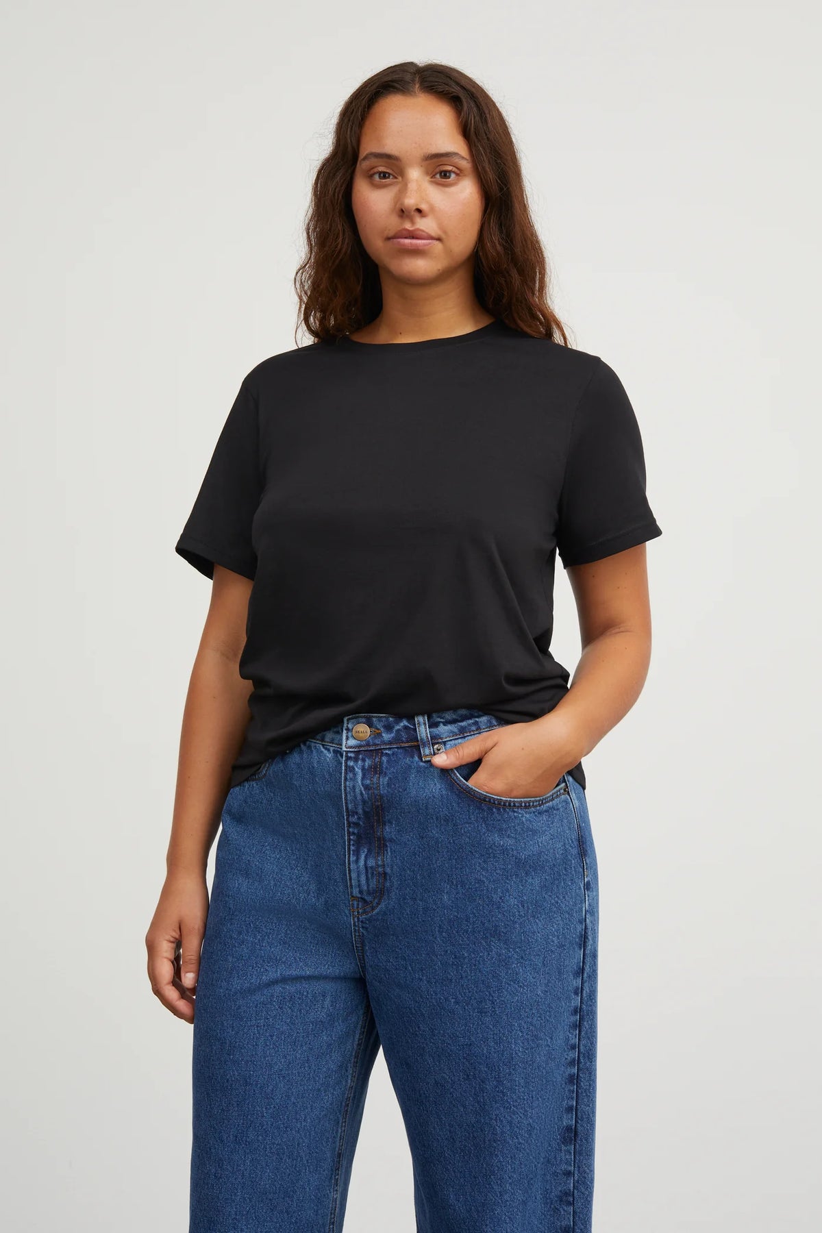 Woman wearing a black t-shirt and blue jeans on a white background