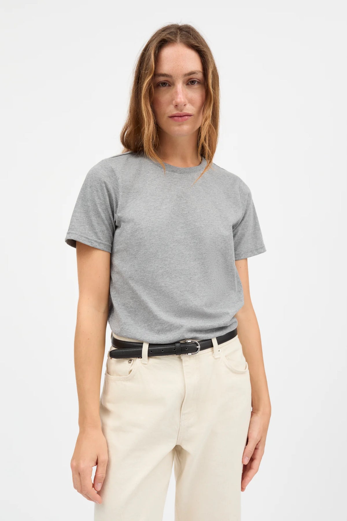 Woman wearing a gray t-shirt and white pants on a white background