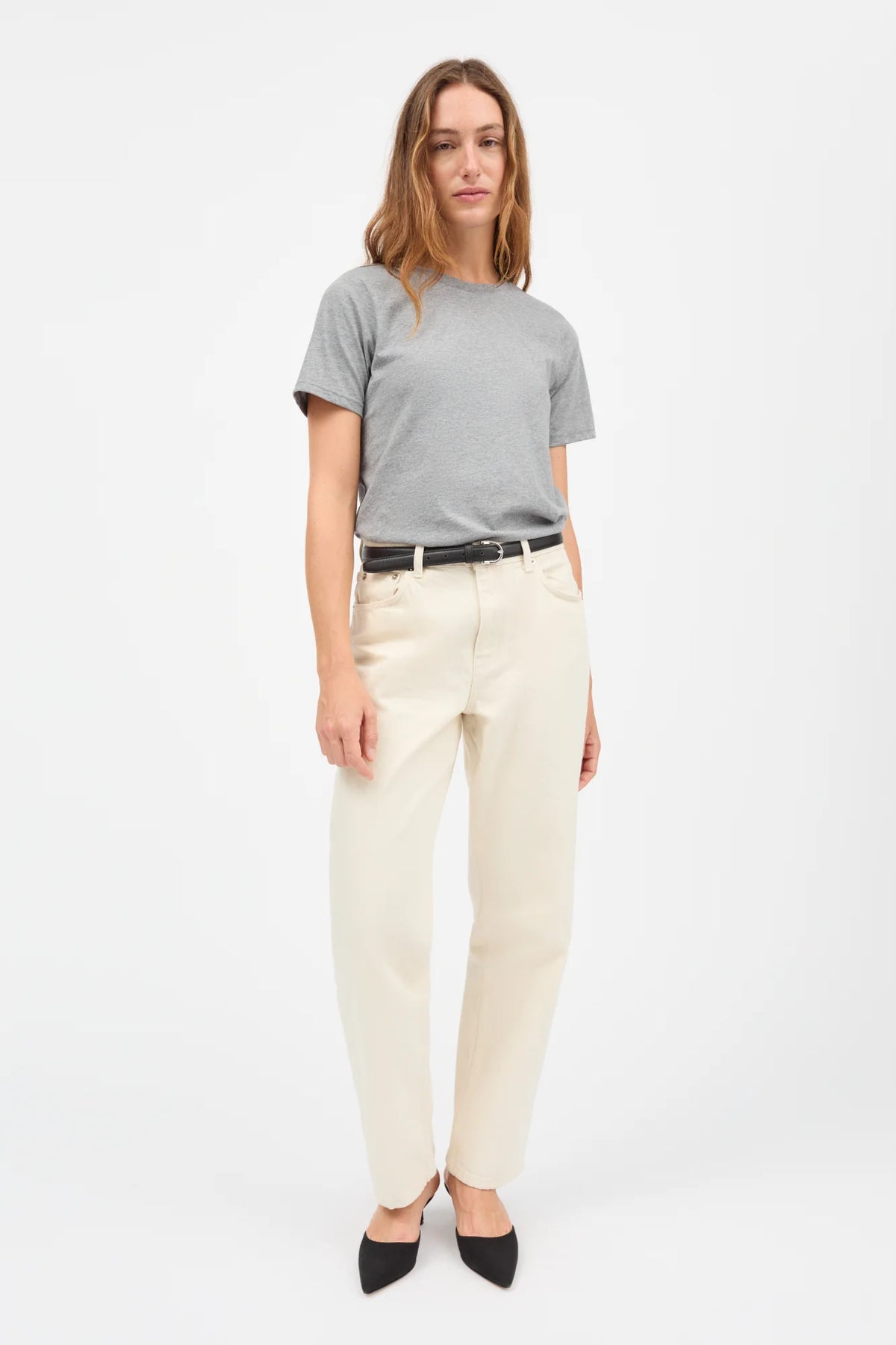 Woman wearing a gray t-shirt and beige pants on a white background