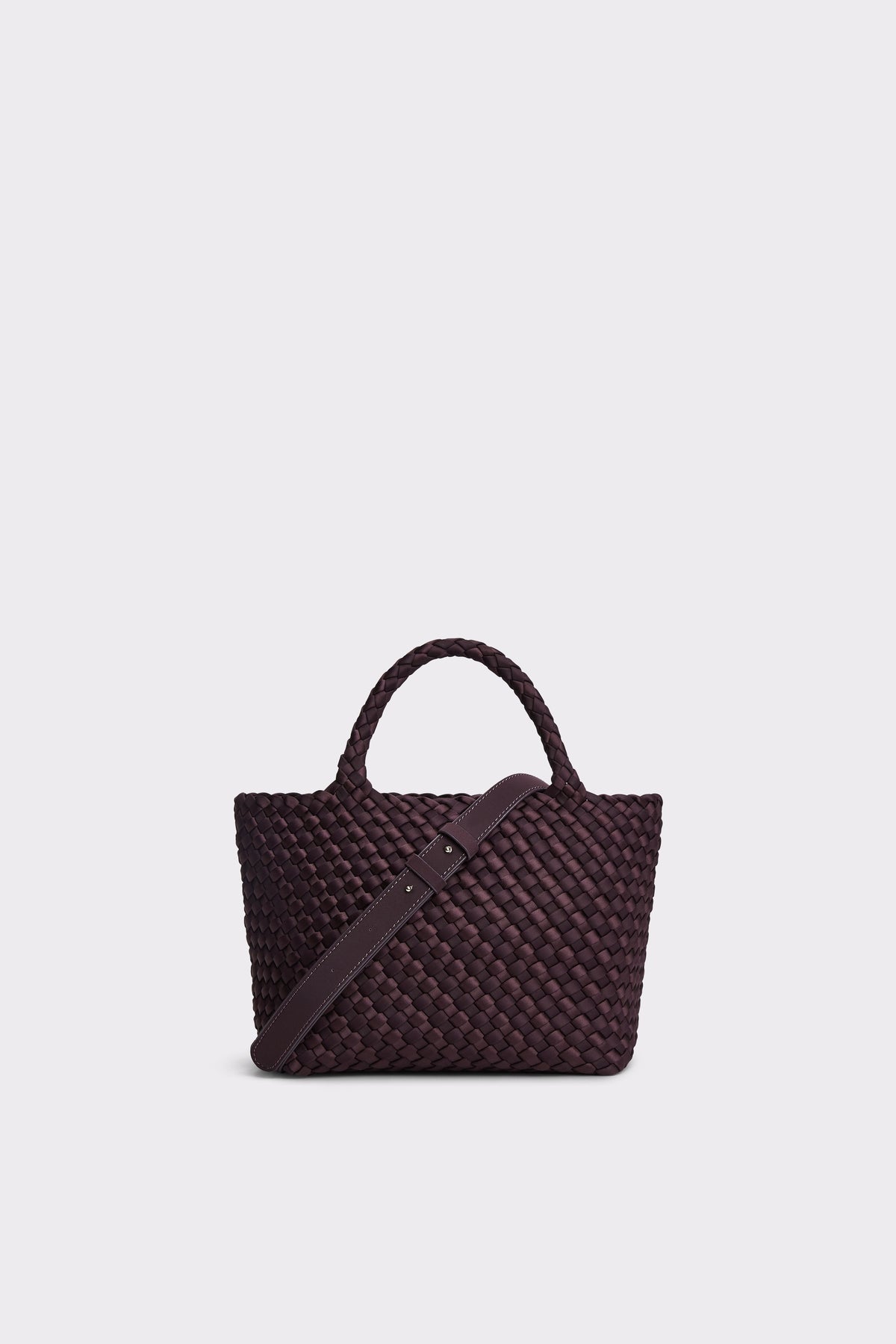 A dark plum purple woven leather tote bag with a matching shoulder strap, displayed against a solid light gray background.