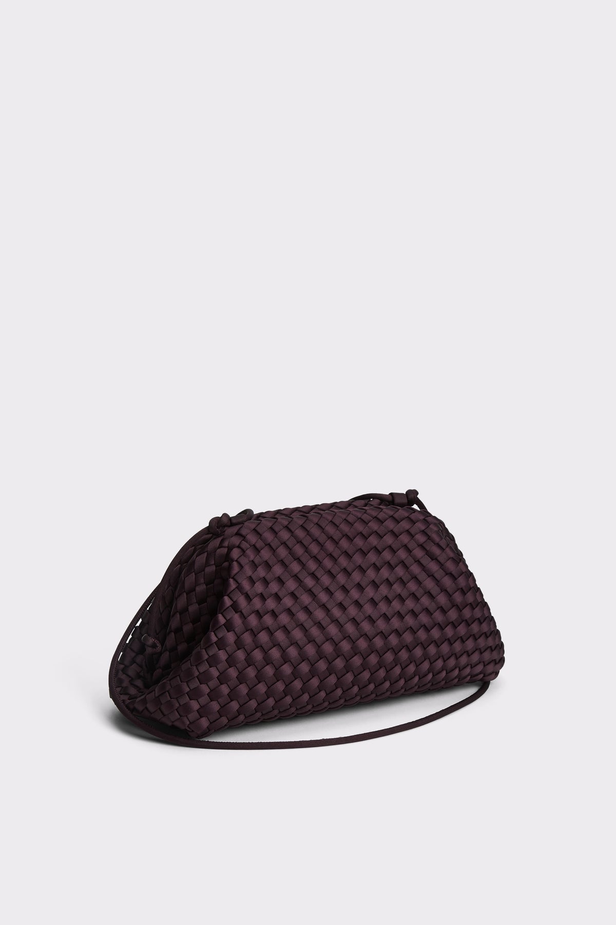A dark plum purple woven leather clutch bag with a thin black shoulder strap, photographed on a light gray studio background.