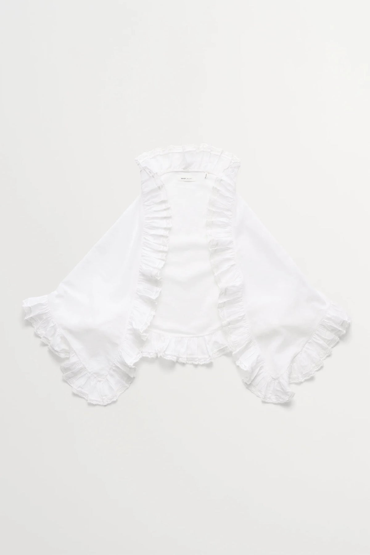 A white sleeveless blouse with ruffled trim along the neckline, front opening, and wide flared sleeves, laid flat against a light off-white background.