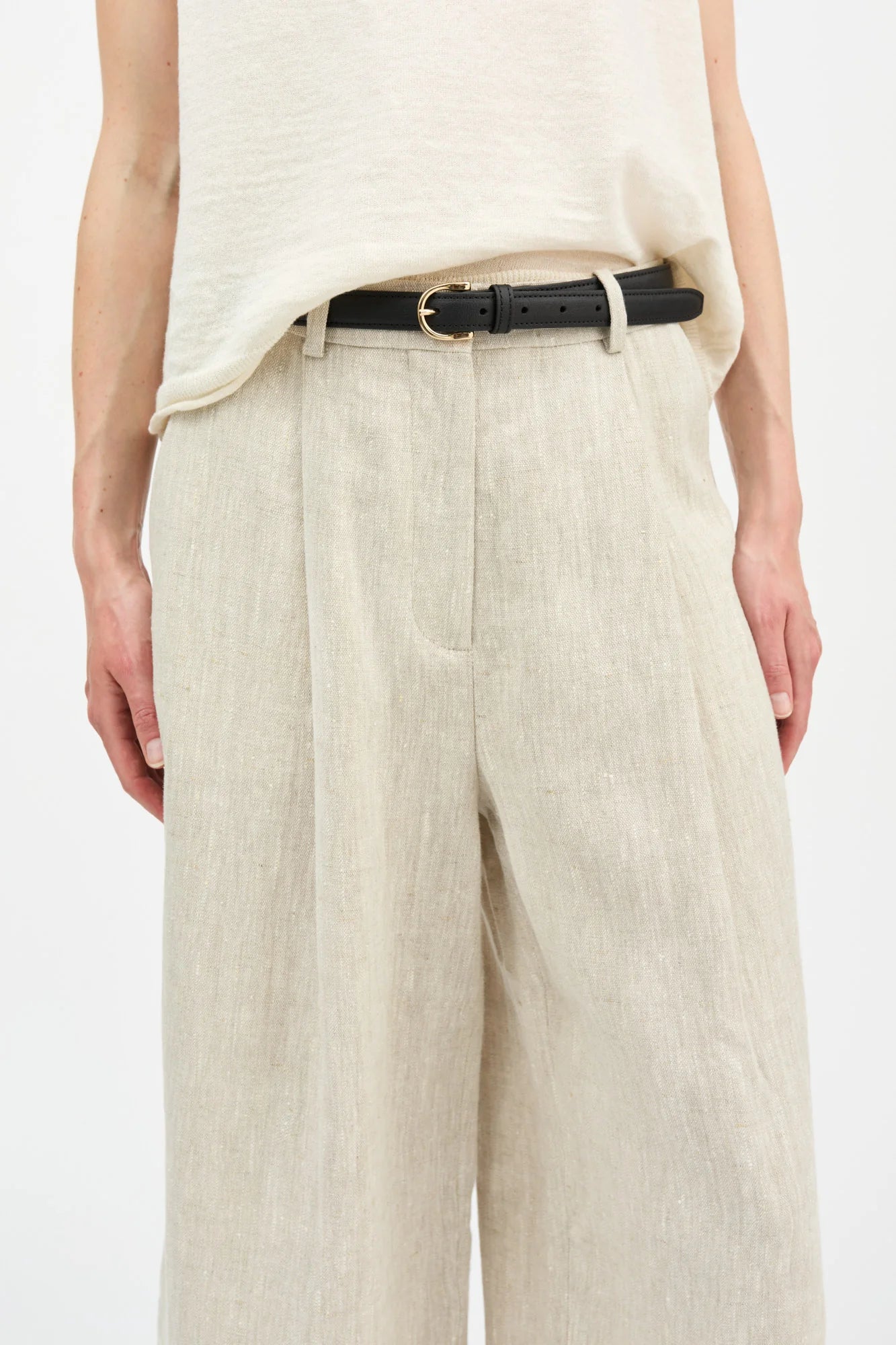 Person wearing beige pants with a black belt on a white background