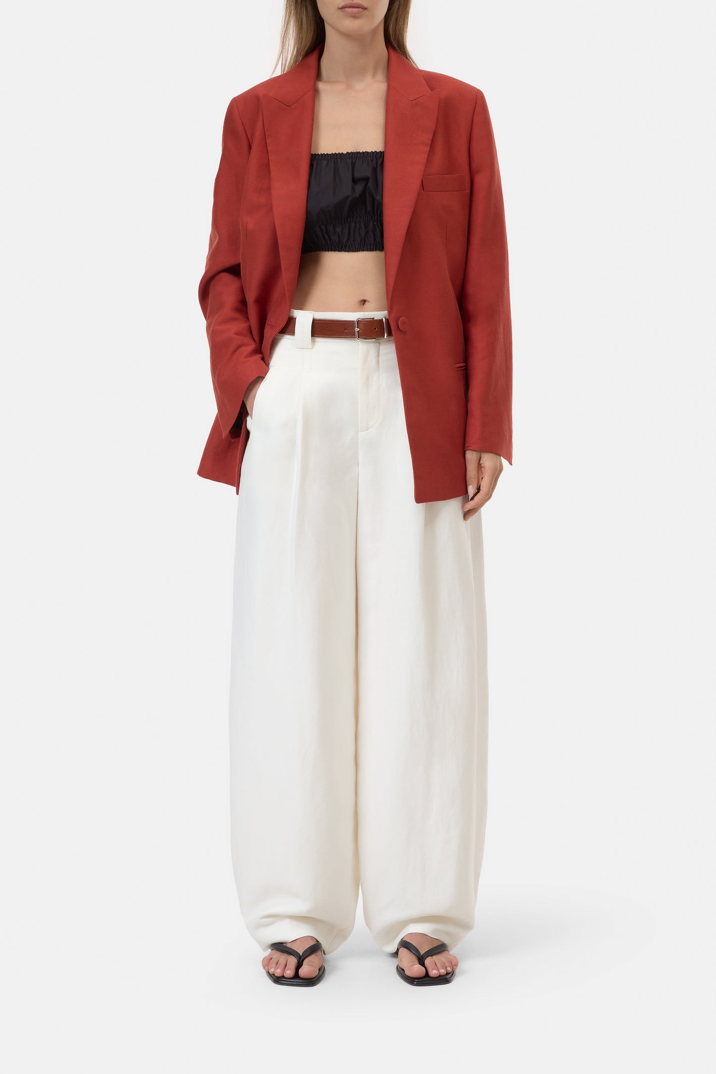 Person wearing a blazer and white wide-leg pants on a white background