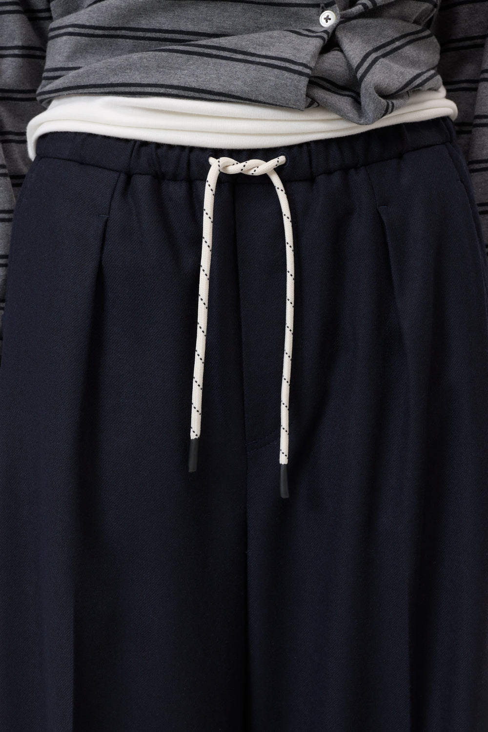 Dark pants with a white drawstring on a neutral background