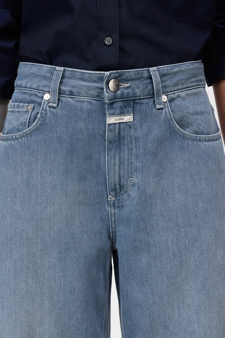 Close-up of blue jeans with a brand label on a white background