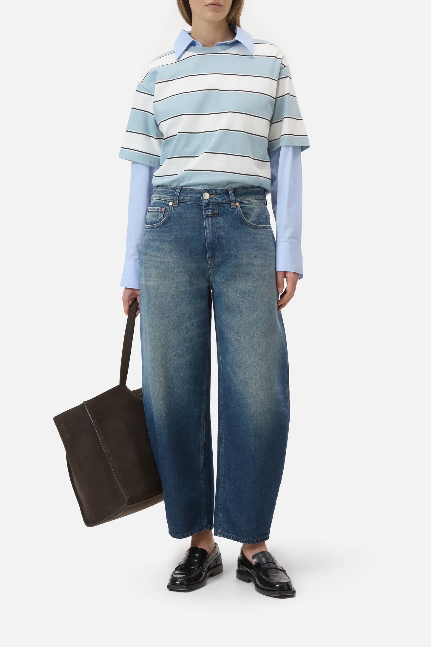Person wearing a striped shirt, jeans, and holding a bag on a white background