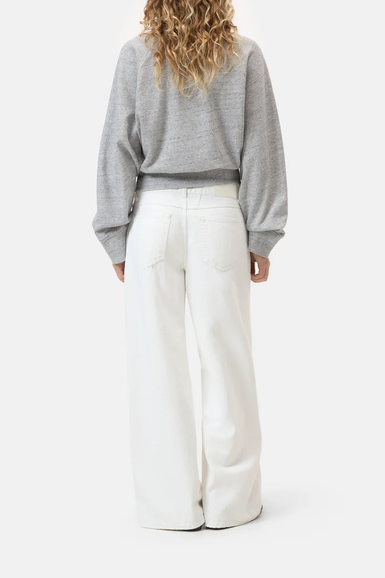 Person wearing a gray sweater and white pants on a white background