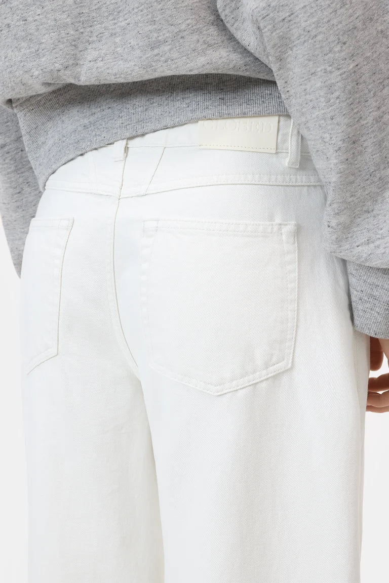 White pants worn with a gray sweater on a white background