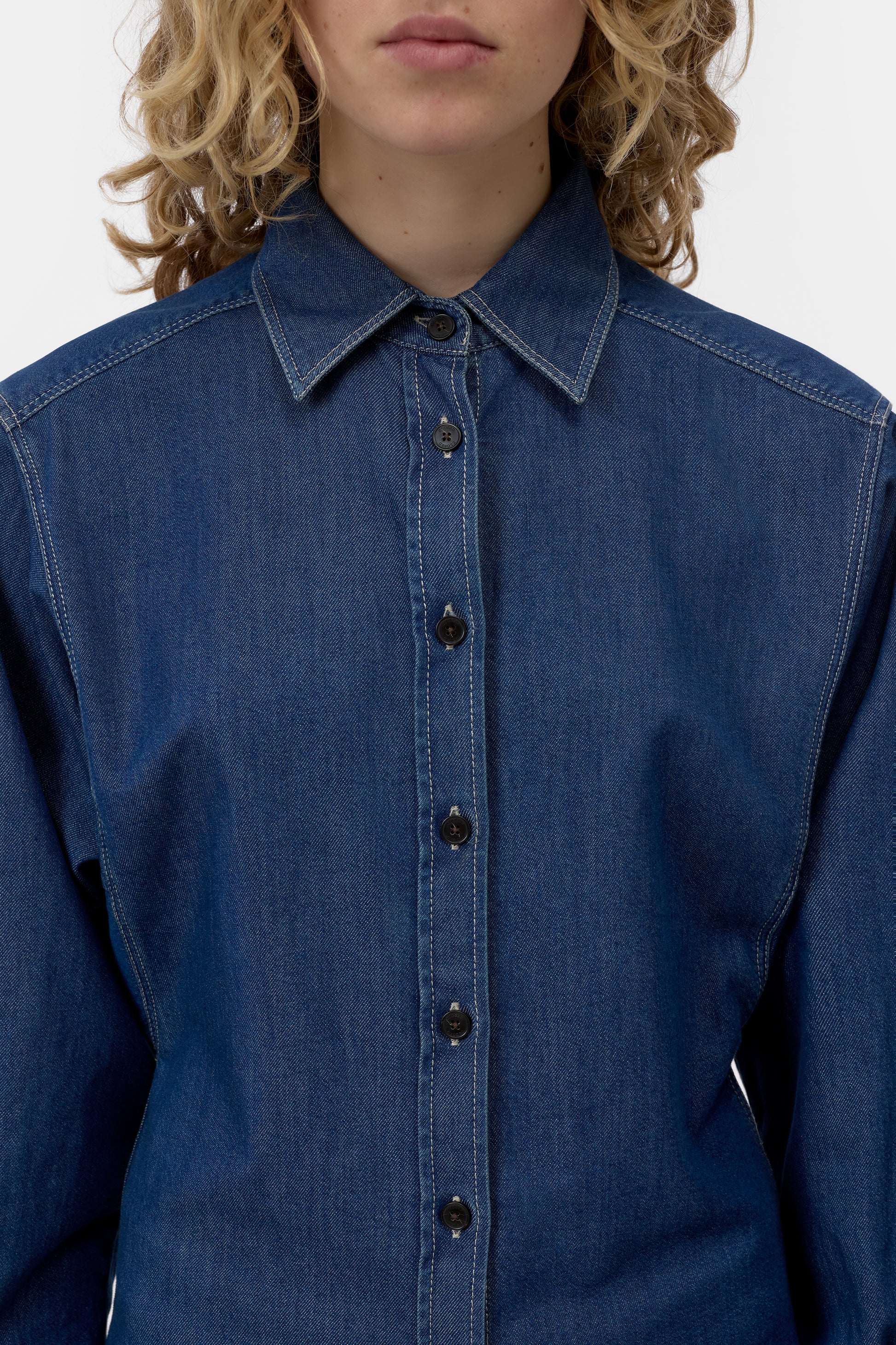 Blue denim shirt worn by a person on a white background