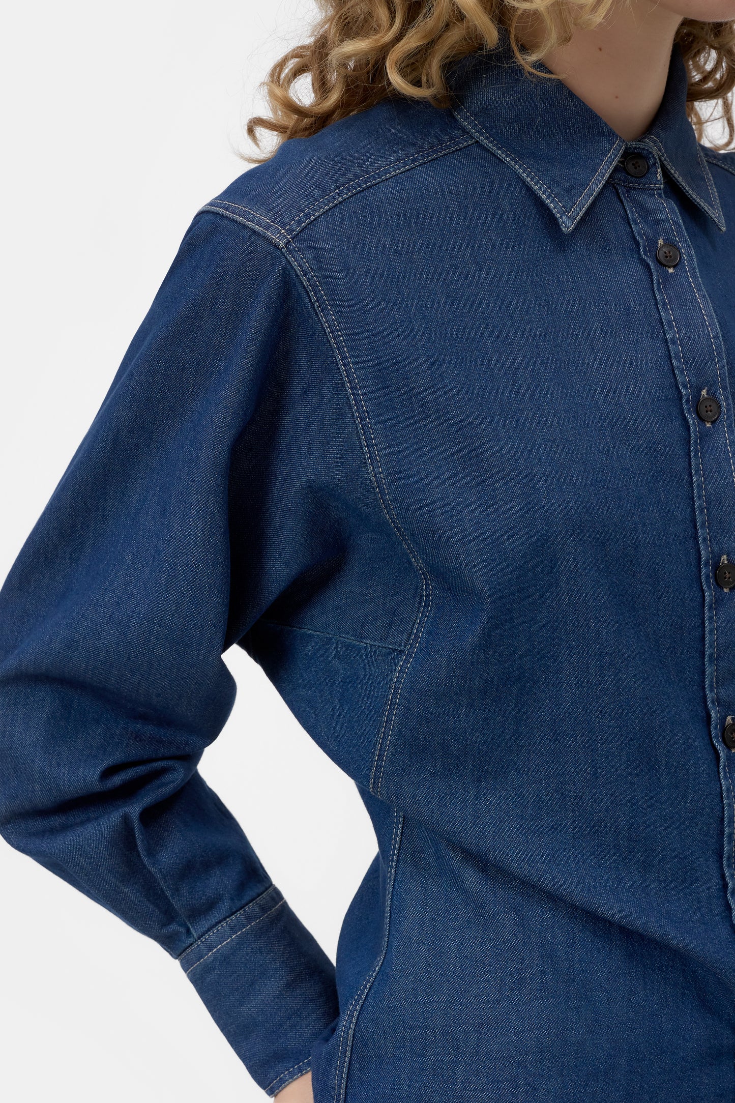 Blue denim shirt worn by a person on a white background