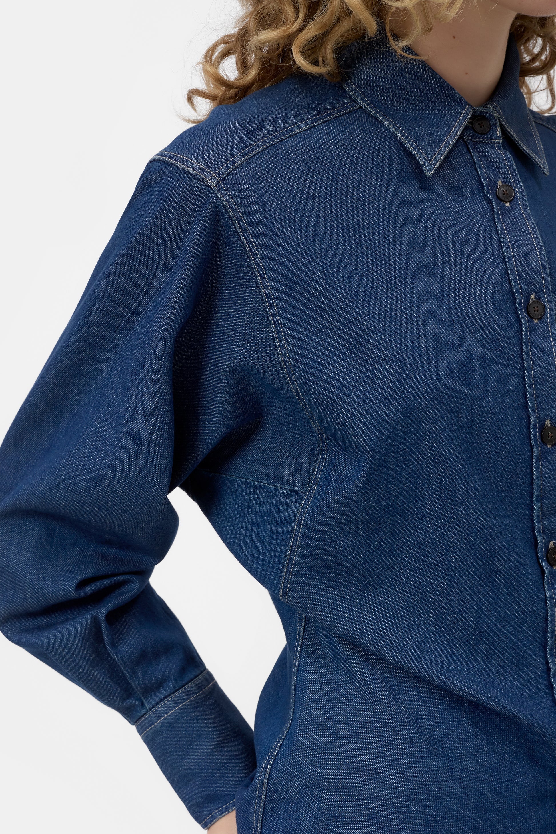 Blue denim shirt worn by a person on a white background