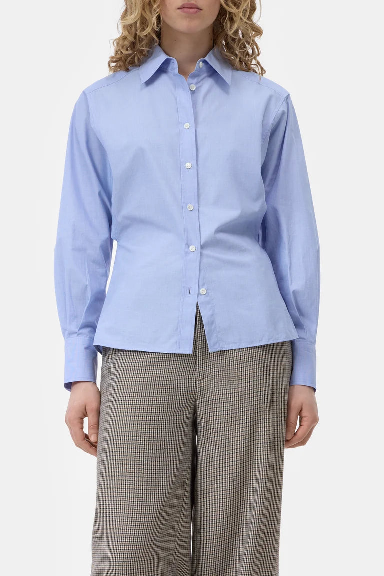 Woman wearing a light blue shirt and plaid pants on a white background