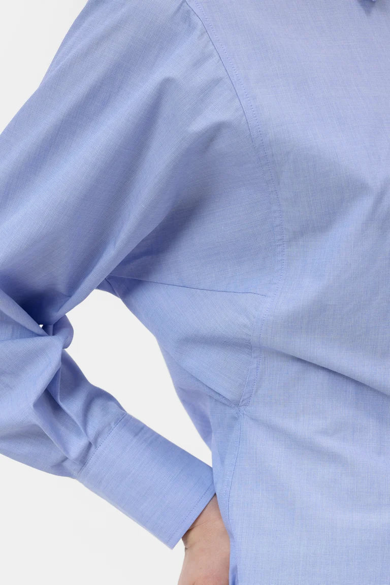 Close-up of a light blue shirt with rolled-up sleeves on a white background
