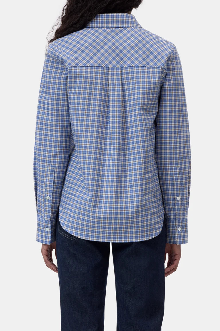 A person shown from the back wearing a blue and white plaid button-up shirt with dark navy pants, photographed against a light gray studio background.