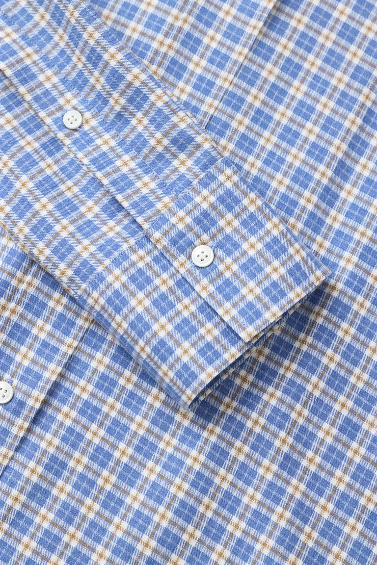 Close-up of a blue and beige plaid button-down shirt showing the fabric texture and cuff details.