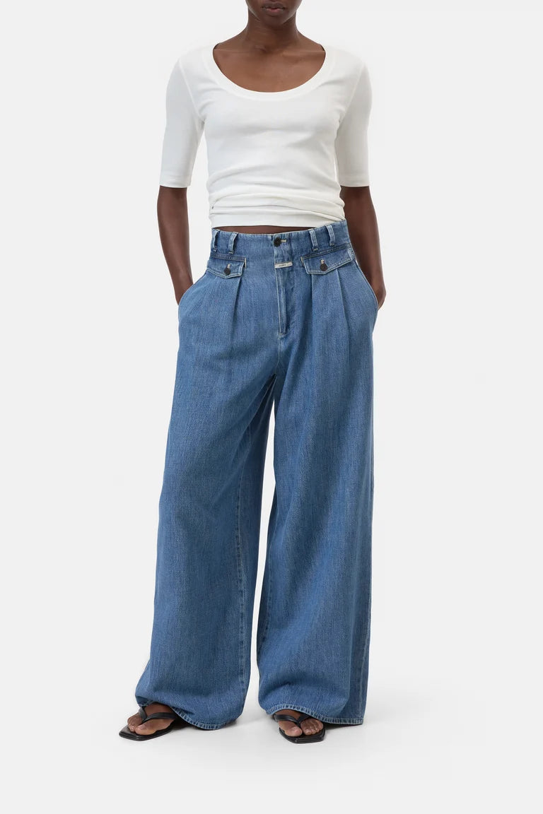 Person wearing a white top and blue wide-leg jeans on a white background
