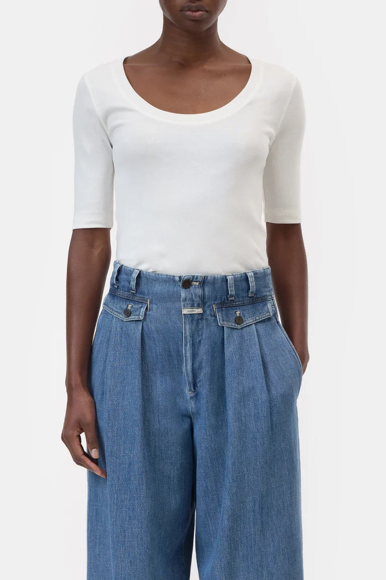 Person wearing a white top and blue jeans on a plain background