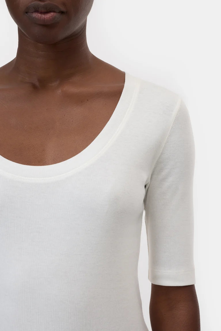 White top worn by a person on a plain background