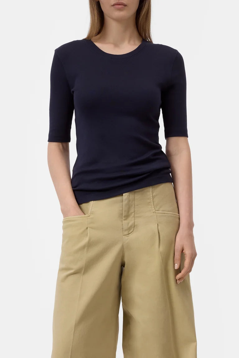 Person wearing a navy blue top and beige pants on a white background