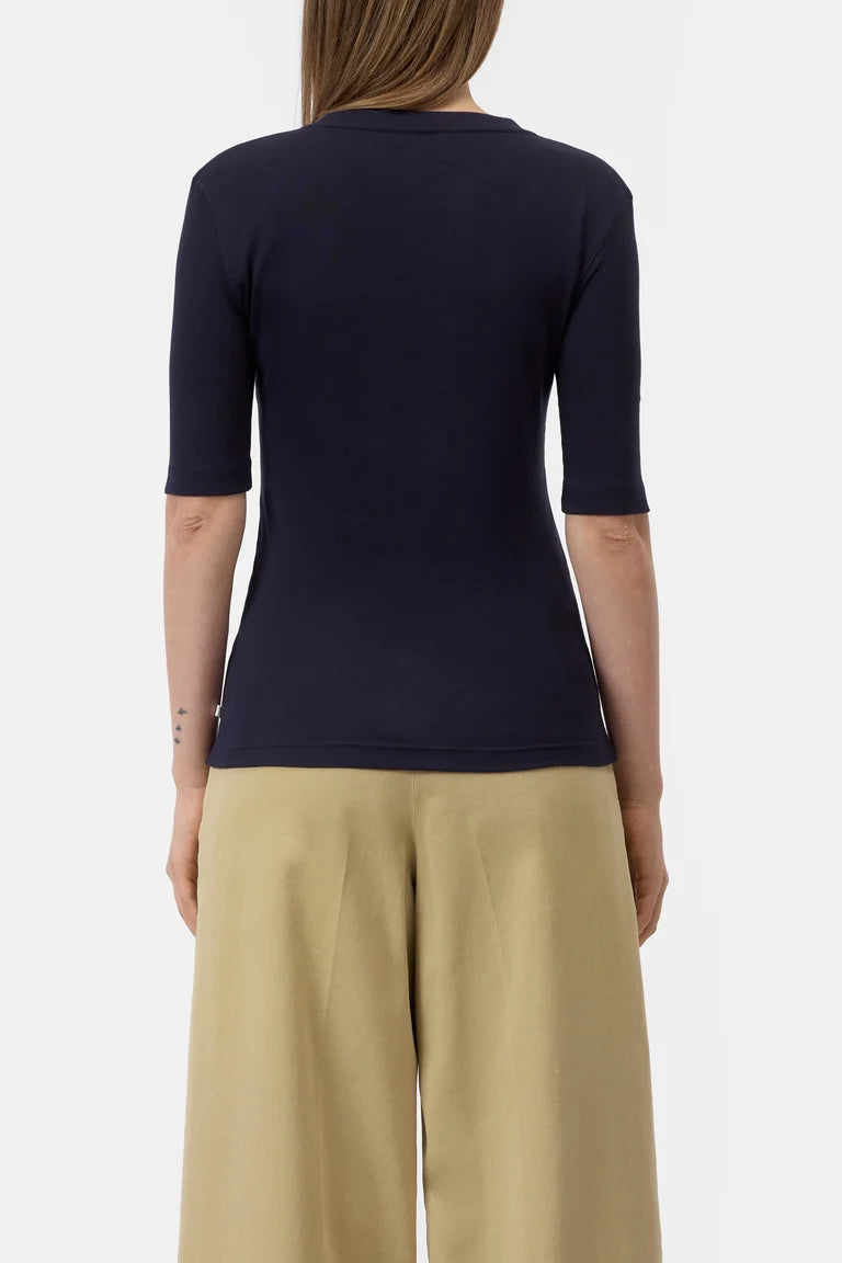 Person wearing a navy blue top and beige pants on a white background